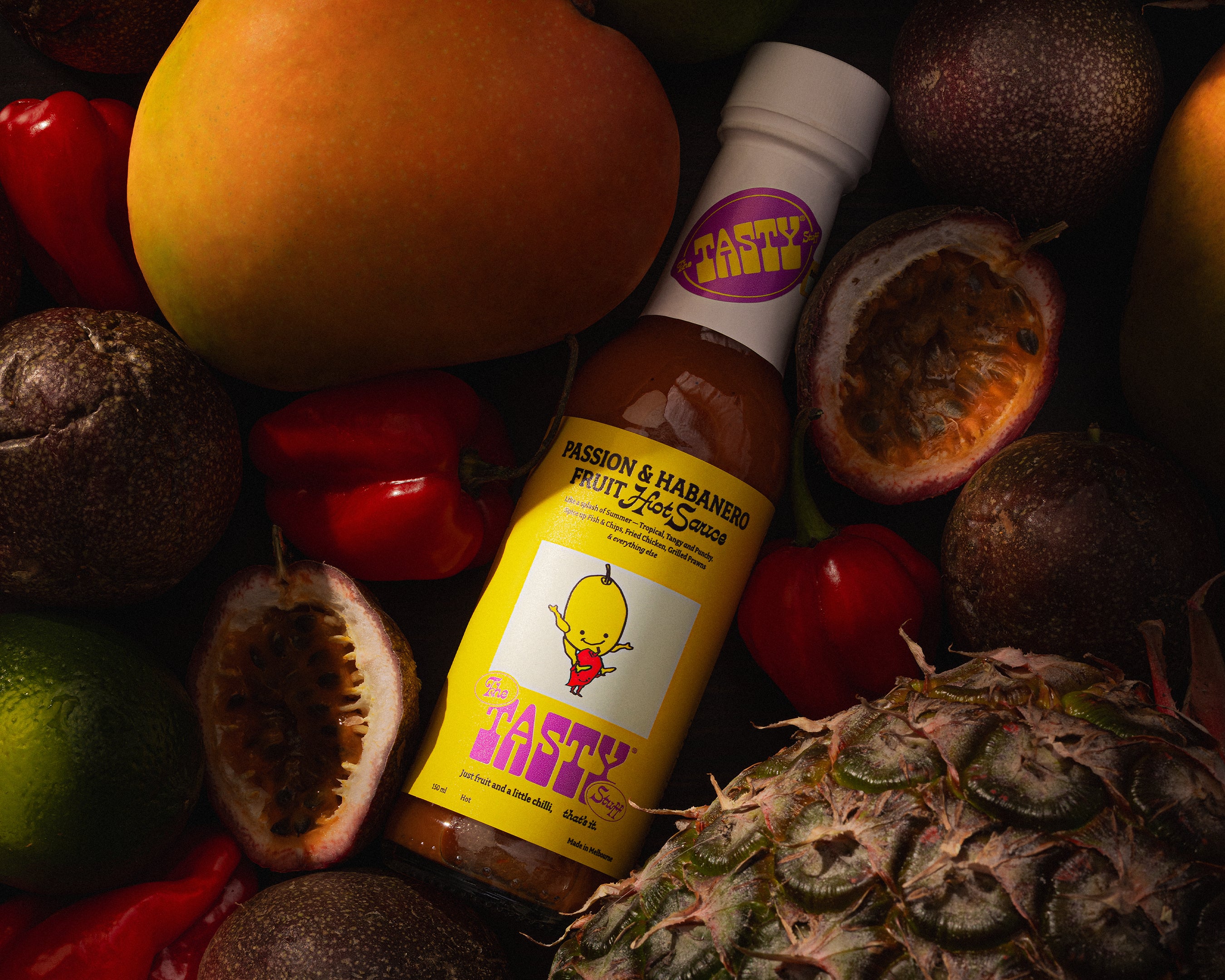 Passion & Habanero hot sauce bottle surrounded by fruits on a dark background